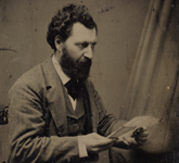 Photo en noir et blanc de Louis Riel assis devant un bureau, vers 1875