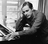 Photo en noir et blanc de Glenn Gould s'appuyant sur un piano et se tenant la tête de la main droite.